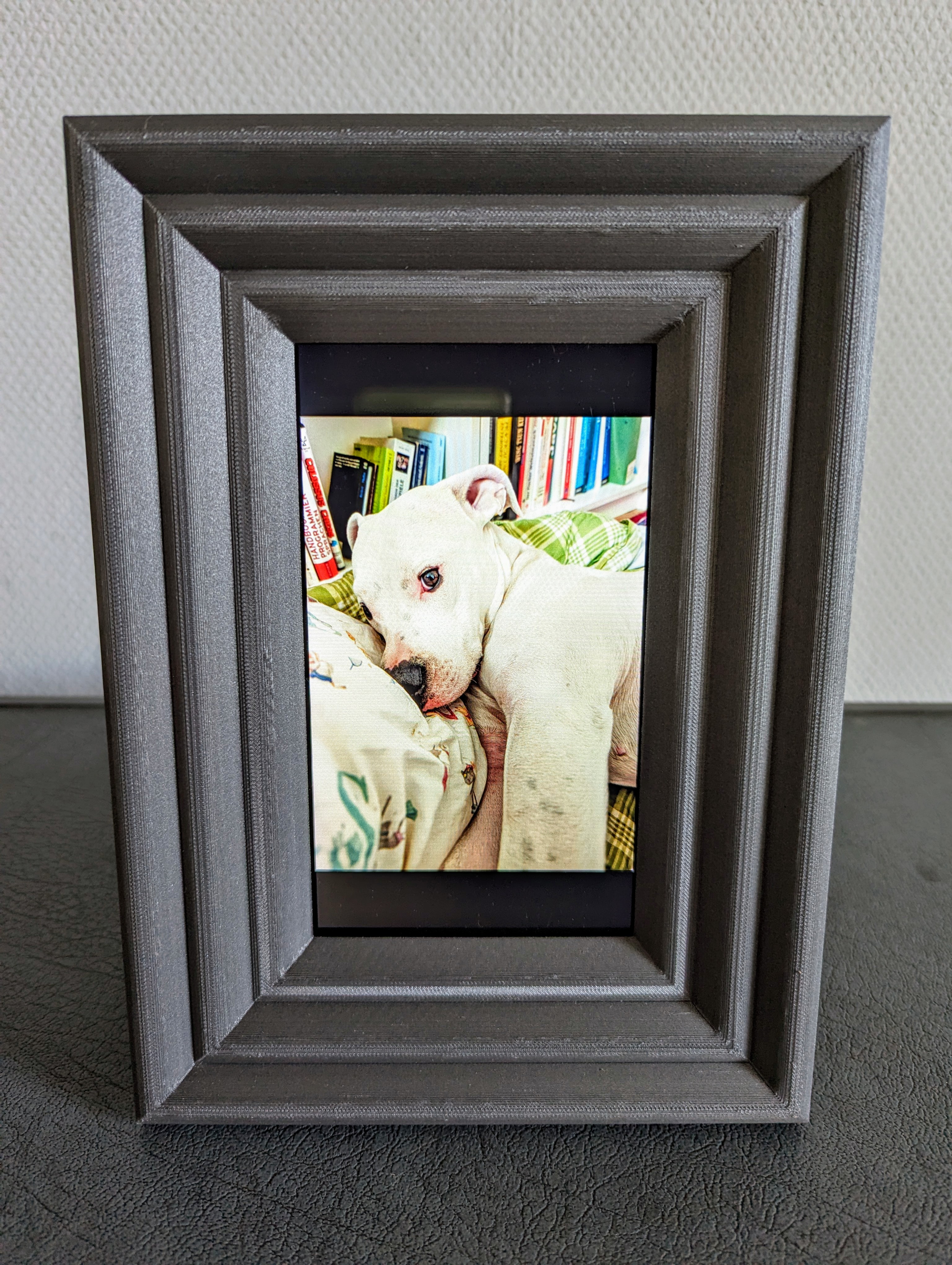 Digital photo frame with a 3d printed passpartout standing on a cupboard.